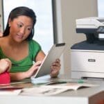 Xerox® VersaLink® B415 Multifunction Printer en situation au travail Deux femmes utilisant une tablette devant une imprimante multifonction Xerox® VersaLink® B415